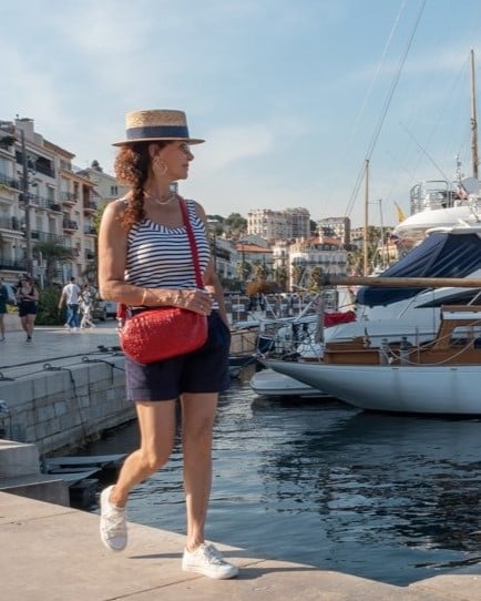 Femme qui marche le long du port de Cannes, avec un petit sac rouge coquelicot porté en bandoulière