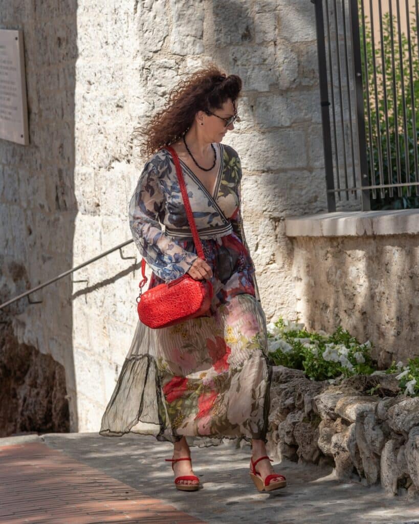 Femme qui marche dans la rue avec un petit sac rouge coquelicot, porté en bandoulière