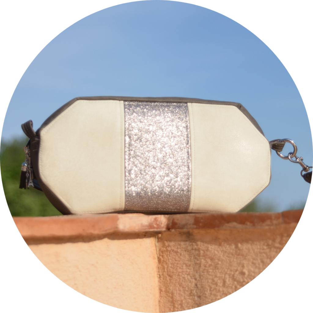 Petit sac bandoulière blanc et argenté, posé sur un mur au soleil