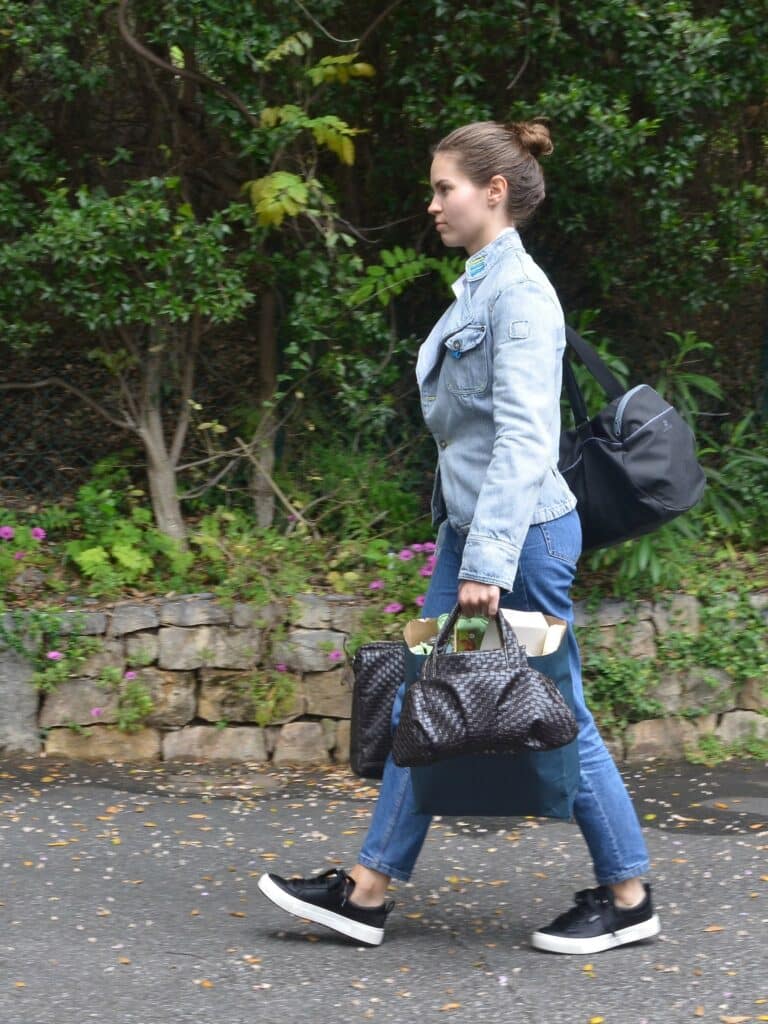 Femme surchargée de sacs qui part de chez elle