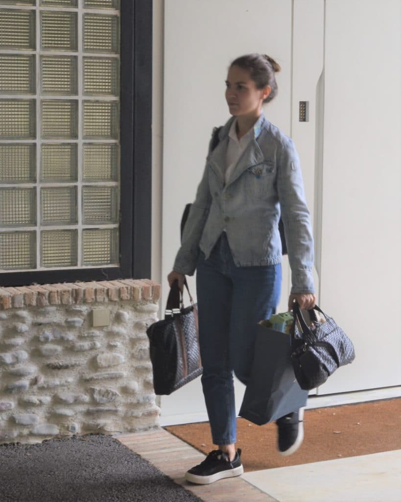Femme surchargée de sacs qui part de chez elle