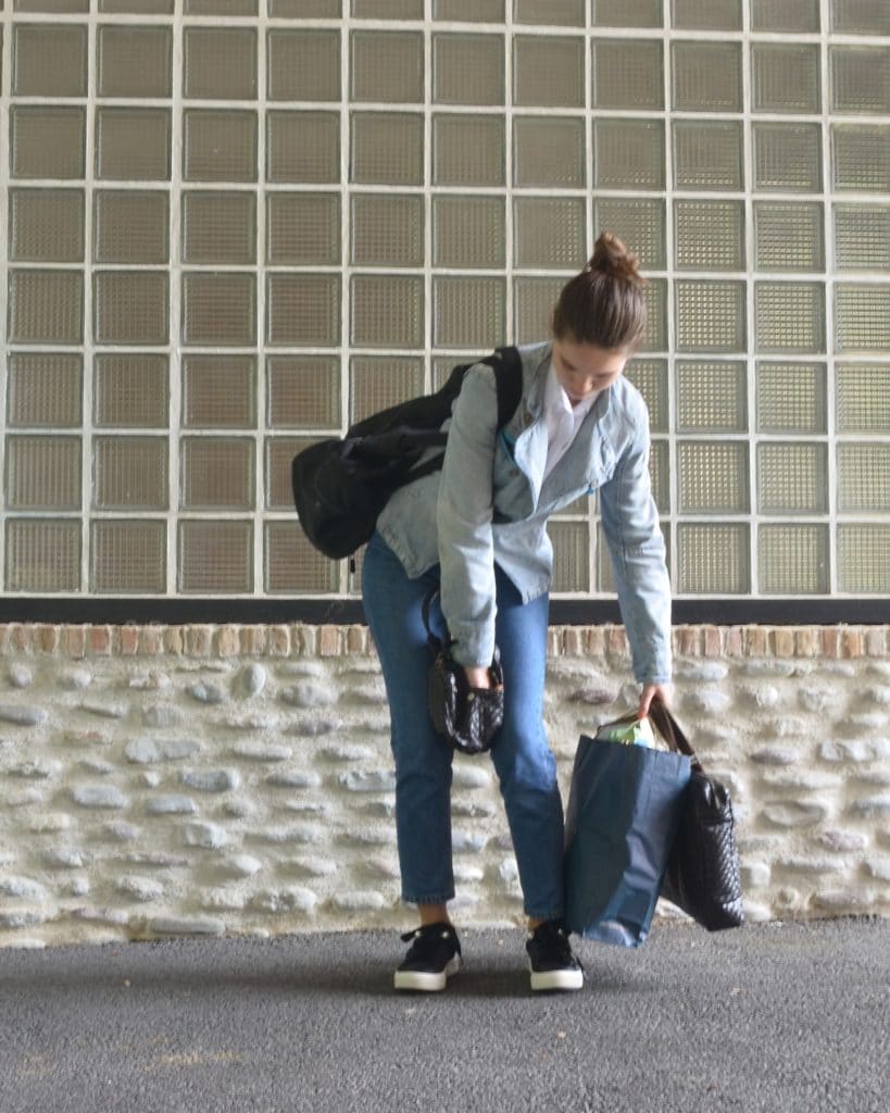 Femme qui a calé son sac à main entre les jambes pour pouvoir y chercher quelque chose