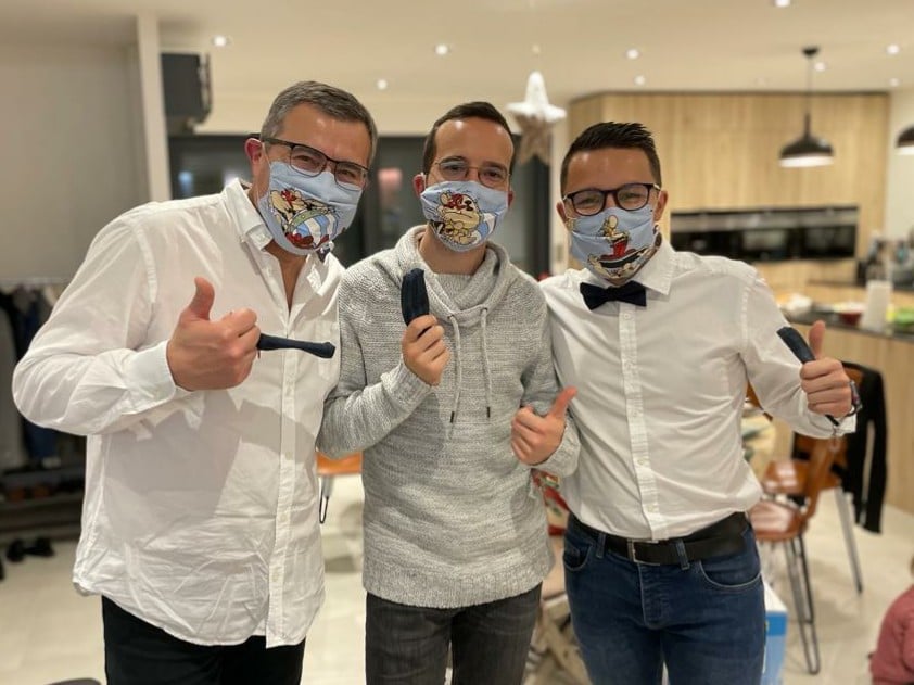 Trois hommes en chemises blanches et jean, avec chacun leur masque en tissu Asterix et leur pochette masque dans la main