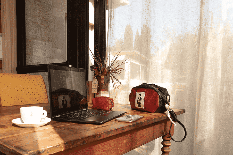 Bureau de coworking, à la librairie café chez mémé, ordinateur, pochette et sac à main sont posée sur une table en bois massif