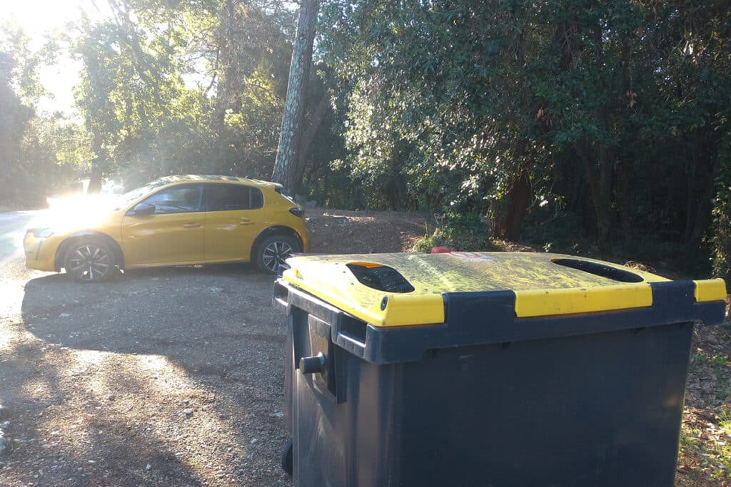 Voiture jaune garé à l'orée de la forte, devant une poubelle avec un couvercle jaune pour les pubelles de récupération du carton, et voiture jaune (inspiration créative)