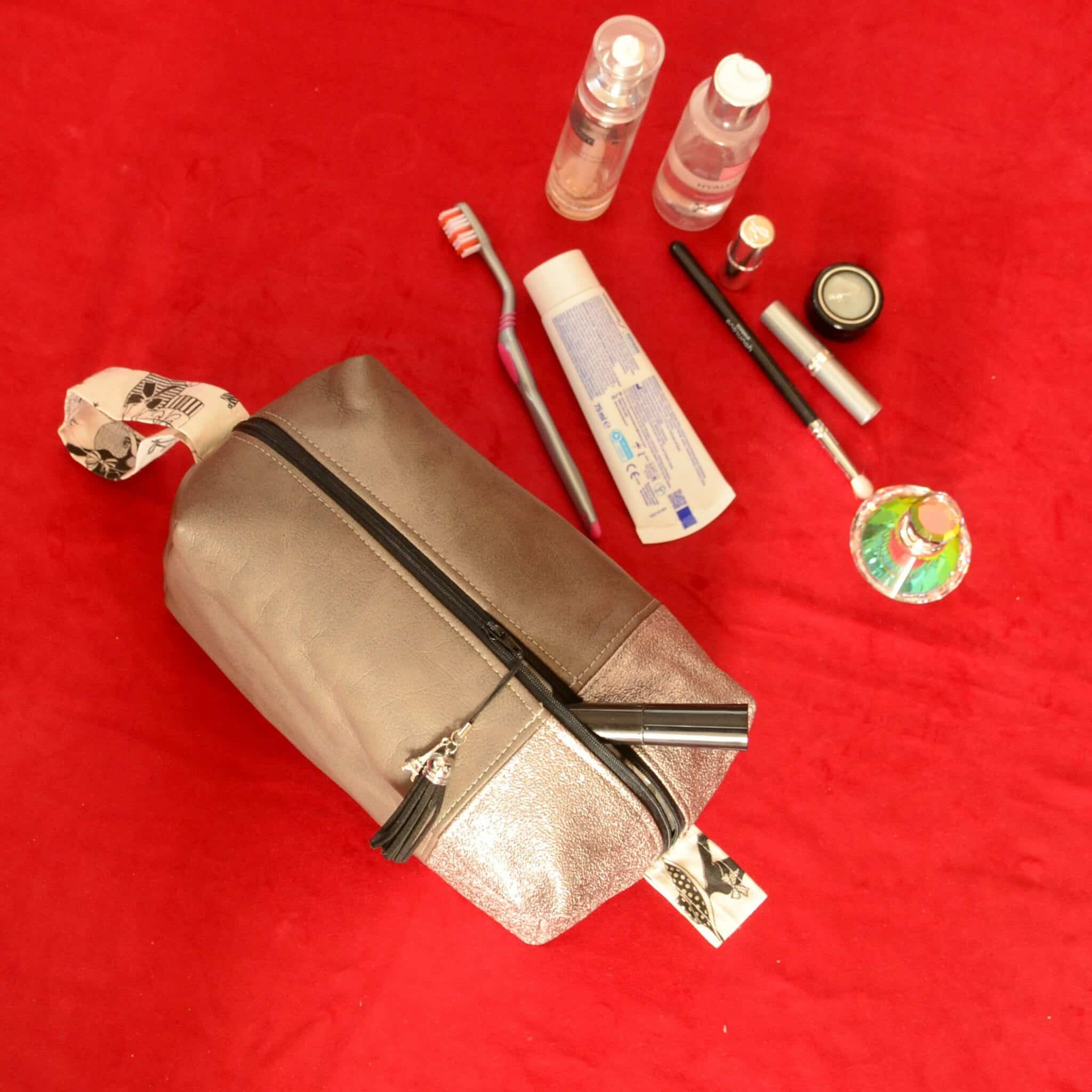 Grande trousse de toilette gris souris et argenté avec tout ce qu'elle peut contenir : brosse à dent, dentifrice, grande bouteille de parfum, etc.